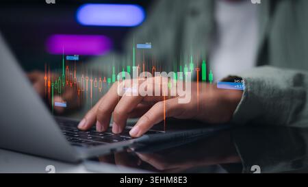 Businessman hands using laptop for trading online with glowing stock market candle graphics. Professional financial analyst monitoring investment data Stock Photo