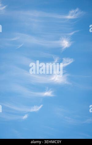 Cirrus clouds forming wispy streaks in blue sky Stock Photo