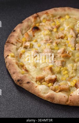 Food, Hawaiian pizza with chicken, pineapple, corn and cheese on dark concrete background Stock Photo