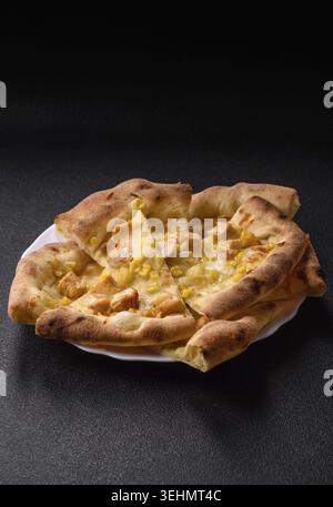 Food, Hawaiian pizza with chicken, pineapple, corn and cheese on dark concrete background Stock Photo