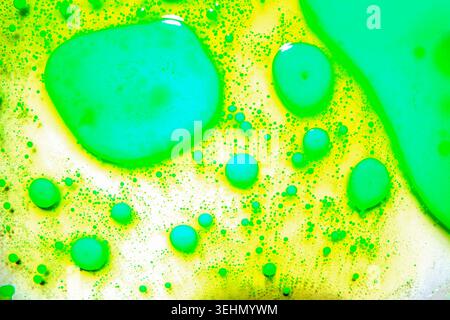 Vivid abstract background of neon green and yellow oil bubbles forming floating spheres and droplets. Macro texture with glossy circles, fluid pattern Stock Photo