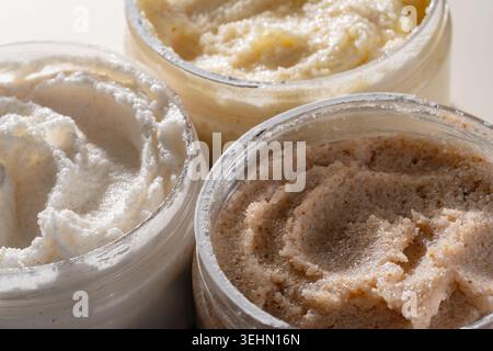 Macro close-up of creamy body scrub texture with gritty exfoliating crystals, swirled and smeared in open cosmetic jars, ideal for skincare, spa, and Stock Photo