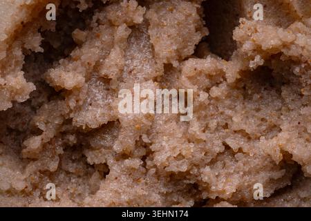 Extreme close-up of a brown body scrub smear showing gritty exfoliating texture. Cosmetic skincare background with granules and creamy paste, ideal fo Stock Photo