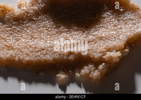Macro close-up of a creamy body scrub smear with grainy exfoliating texture. Natural cosmetic product background showing thick paste, sugar crystals, Stock Photo