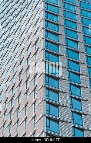 A close-up shot of a modern building facade showcasing geometric patterns with blue-tinted windows. The design highlights contemporary architectural d Stock Photo
