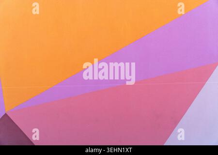 Abstract colorful wall mural with overlapping geometric triangles in orange, purple, pink, and gray tones, creating a modern pastel background with cl Stock Photo