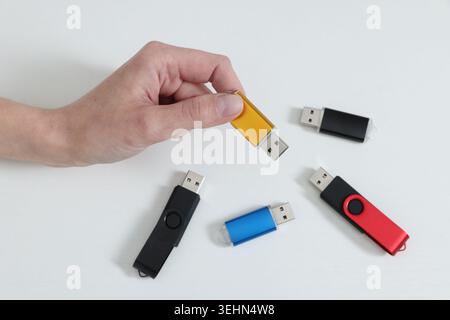 Woman with many USB flash drives on light background, closeup Stock Photo