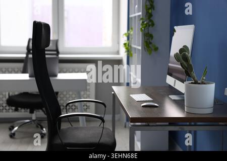 Desks with computers, chairs, shelving unit and decor in office. Interior design Stock Photo