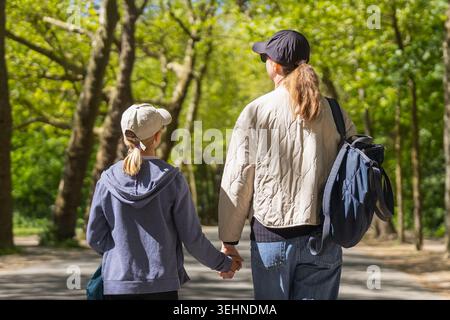 A mother and daughter holding hands while walking through a park in Amsterdam during their spring vacation. Stock Photo