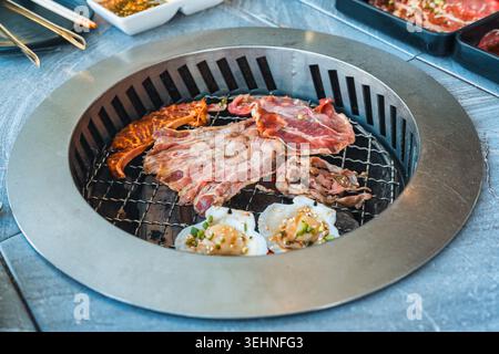 Assorted various type of premium meats including marbled beef, seafood grilling on BBQ charcoal grill at barbecue restaurant Stock Photo