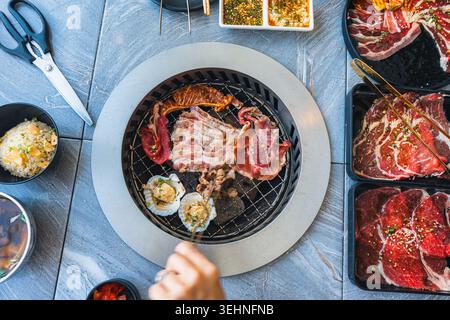 Assorted various type of premium meats including marbled beef, seafood grilling on BBQ charcoal grill at barbecue restaurant Stock Photo