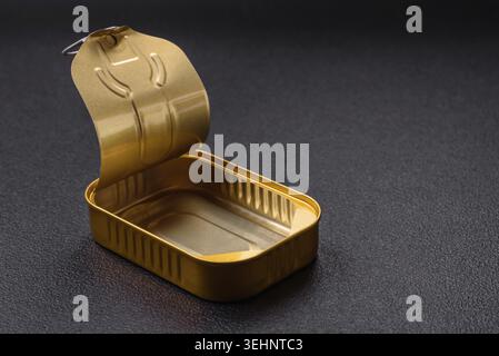 Food, Tin or aluminum opened rectangular can of canned food with a key on a dark concrete background Stock Photo