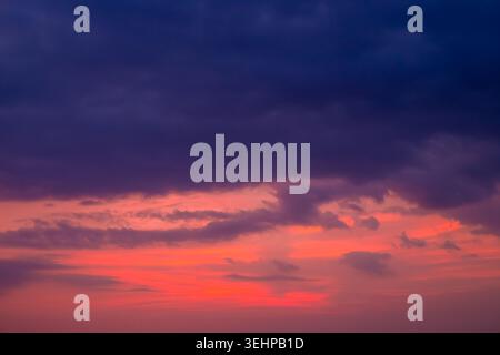 Dramatic sunset sky with dark purple clouds and vibrant orange and pink hues. sunset sky, dramatic clouds, colorful sky. Stock Photo