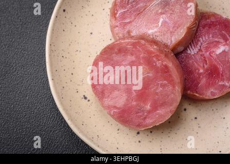 Food, Round shape steaks of raw juicy tuna with salt and spices on a dark concrete background Stock Photo
