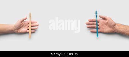 Two hands holding plastic and bamboo toothbrushes on white Stock Photo
