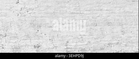 White painted brick wall with peeling paint and grunge texture creating a textured background Stock Photo
