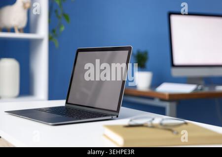 Desks with computers, glasses, stationery and decor in office, closeup Stock Photo