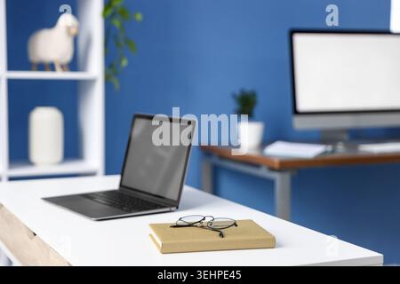 Desks with computers, stationery and decor in office, closeup. Interior design Stock Photo