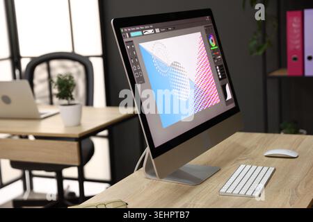 Wooden desks with computers, stationery and plants in office, closeup. Interior design Stock Photo