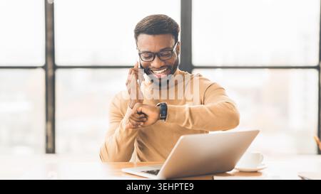 African businessman checking time talking on phone Stock Photo