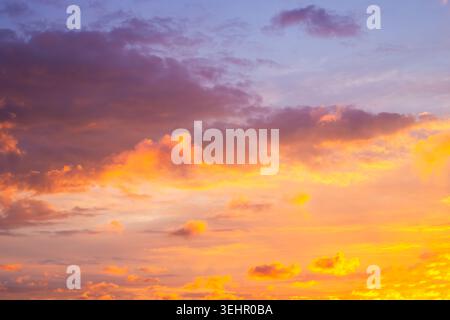 A dramatic sunset sky filled with vibrant orange and purple clouds. beautiful sky background, sunset colors, twilight scenery. Stock Photo