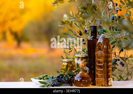 Fragrant olive oil on the table with olive branches and fresh olives Stock Photo