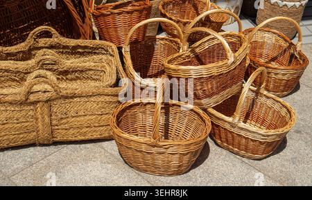 Wicker baskets made from natural materials are arranged on the ground at a market. Shoppers can explore and buy these handcrafted items on a sunny day Stock Photo
