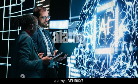 Autonomy concept, AI machine learning and engineering team looking at self writing code on screen, artificial intelligence and teamworking colleagues reviewing self sustaining AI model Stock Photo