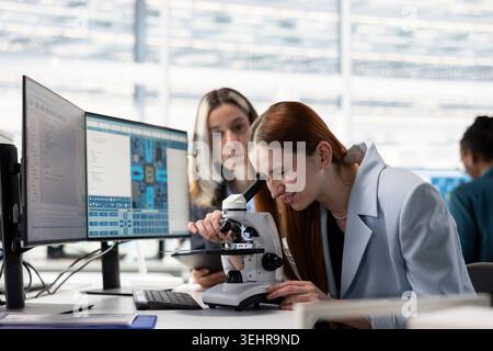 Analyzing nanotechnology circuits, microscope and engineering team in microchip factory RD office, brainstorming. Inspecting PCB parts, optical gear and teamworking colleagues in research facility Stock Photo