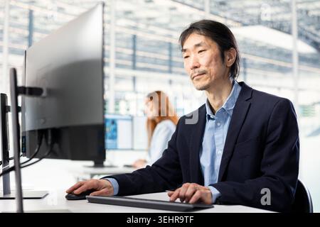 Senior engineer in microchip factory RD office conducting feasibility study on SoC architecture design. Asian man developing roadmaps for innovative semiconductors technology Stock Photo
