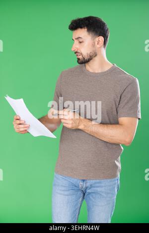 Adult man making notes on paper documents in front of green screen Stock Photo