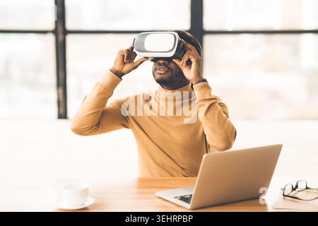 Afro businessman wearing augmented reality goggles at home Stock Photo