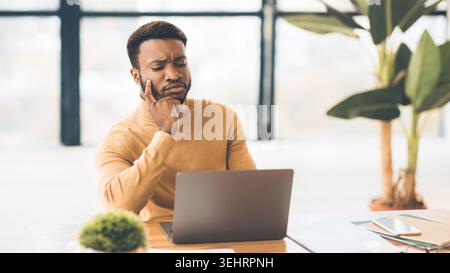 Focused black man working with laptop at office Stock Photo