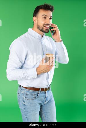 Man with cup of coffee is talking on phone, emotionally communicating with friend Stock Photo