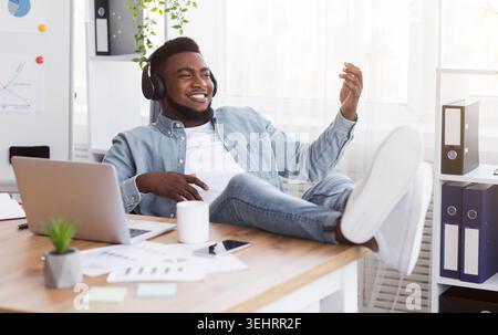 Black worker listening music in office and playing virtual guitar Stock Photo