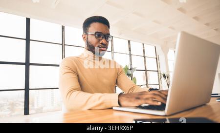Concentrated african american man working with laptop Stock Photo