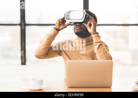 Afro businessman wearing augmented reality goggles at home Stock Photo