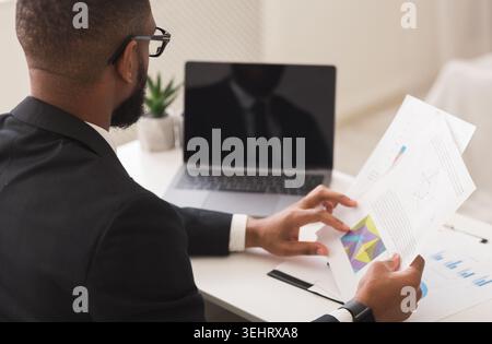 African businessman reading financial reports, working in modern office Stock Photo