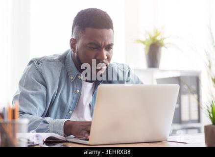 Focused african american employee working on laptop in office Stock Photo