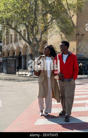 Happy african american students friends man and woman walking smiling through city road together. Stock Photo