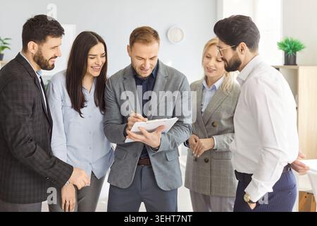 Business people team leader coach mentor talking to diverse business people in office Stock Photo