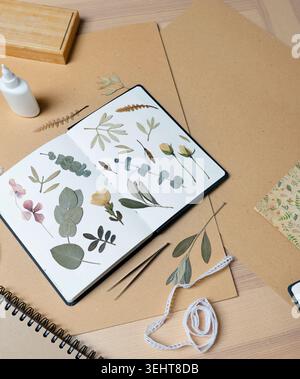 Cozy creative workspace with botanical herbarium notebook olive leaves eucalyptus. Artistic flat lay composition featuring dried plants stationery Stock Photo