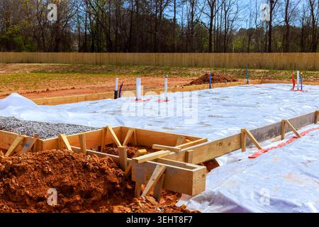 Construction workers prepare foundation by setting wooden forms laying plastic sheeting Stock Photo