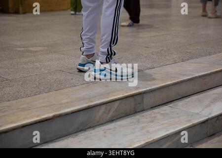 BANGKOK, THAILAND-MAY 16, 2026: Man in white sneakers standing on marble floor, Nike sneakers, unposed movement, candid motion, high angle view Stock Photo
