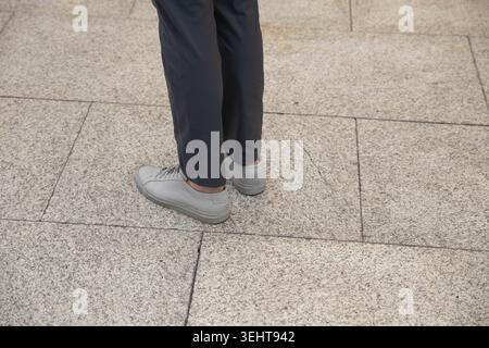Man in grey sneakers standing on floor, unposed movement, natural candid motion, high angle view Stock Photo