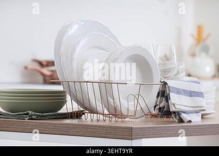 Dryer with clean dishes on counter in kitchen Stock Photo