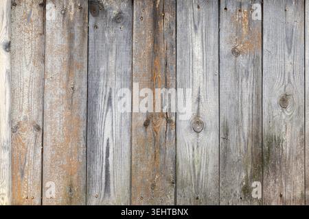 Vertical weathered wooden planks creating a rustic fence texture. The natural wood grain and knots provide a simple yet captivating abstract pattern. Stock Photo