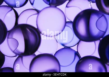 Multiple transparent liquid spheres creating vibrant purple science abstract background Stock Photo