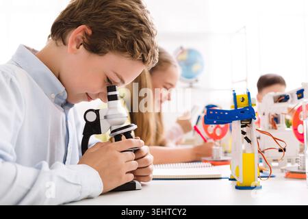 Students Engaged in Hands On Learning With Microscopes and Robotics in a Bright Classroom Stock Photo