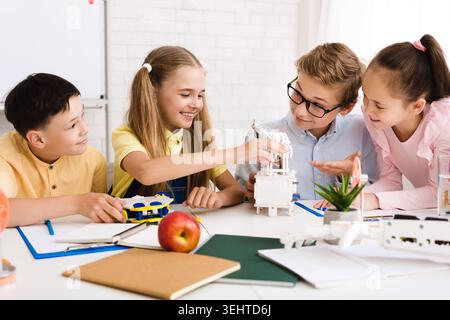Kids Engaged in a Creative Group Project at a Classroom Desk During a Sunny Afternoon Stock Photo